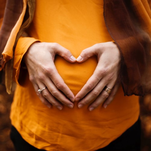 Kvinna som håller händerna över sin gravida mage.
